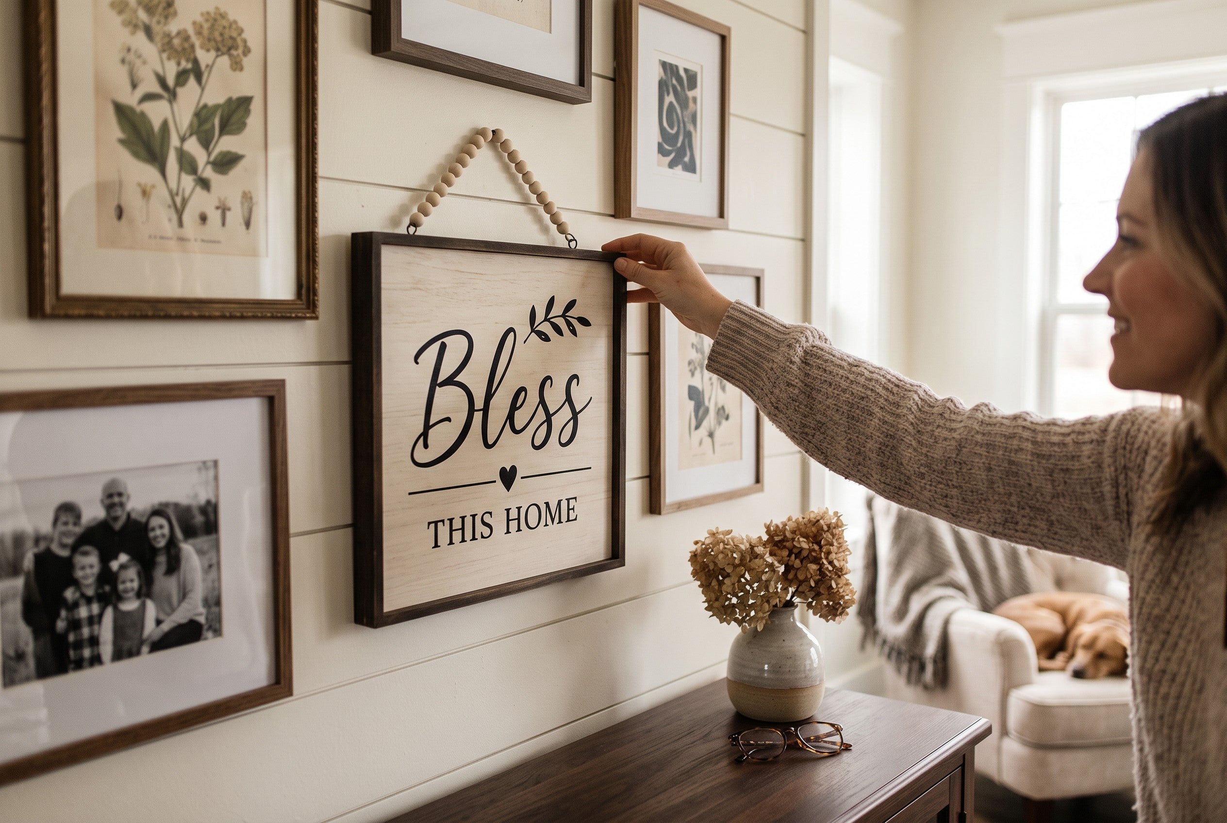 Keepsake lane farmhouse wall sign with Bless This Home text and beaded hanger held by a woman in a cozy living room.