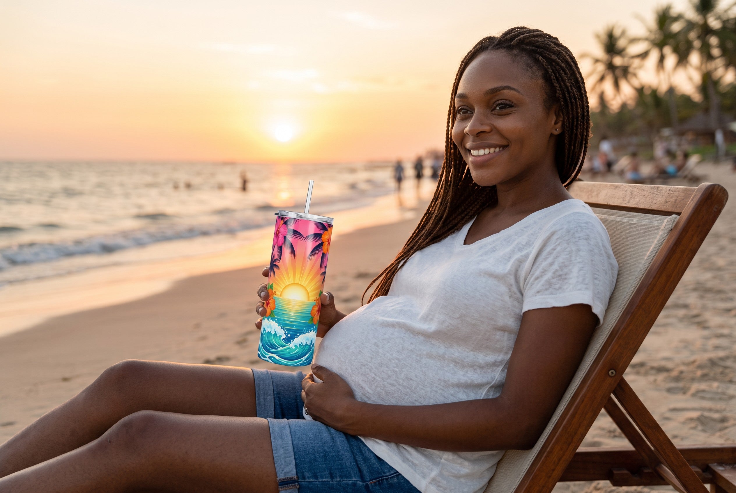 Keepsake lane stainless steel tumbler with tropical sunset print held by a pregnant woman on a beach at sunset.